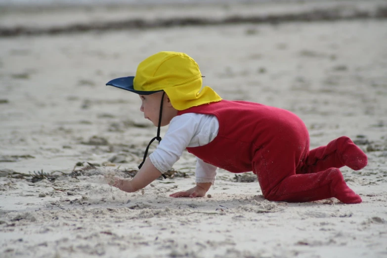 a child wearing a red and yellow outfit and a blue hat