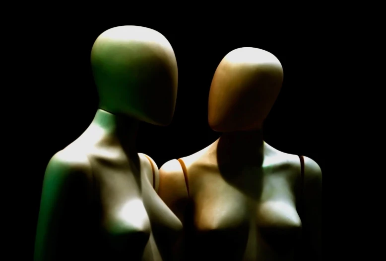 two mannequins in the dark facing away from each other