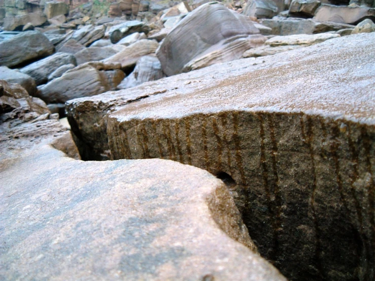 the rock formation in the desert is shown with a rock wall and large, dark boulder