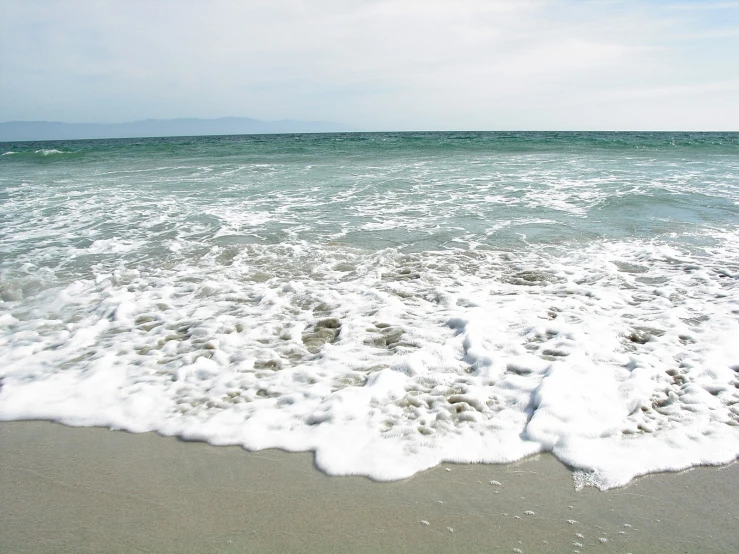 some waves are coming in the sand on a beach