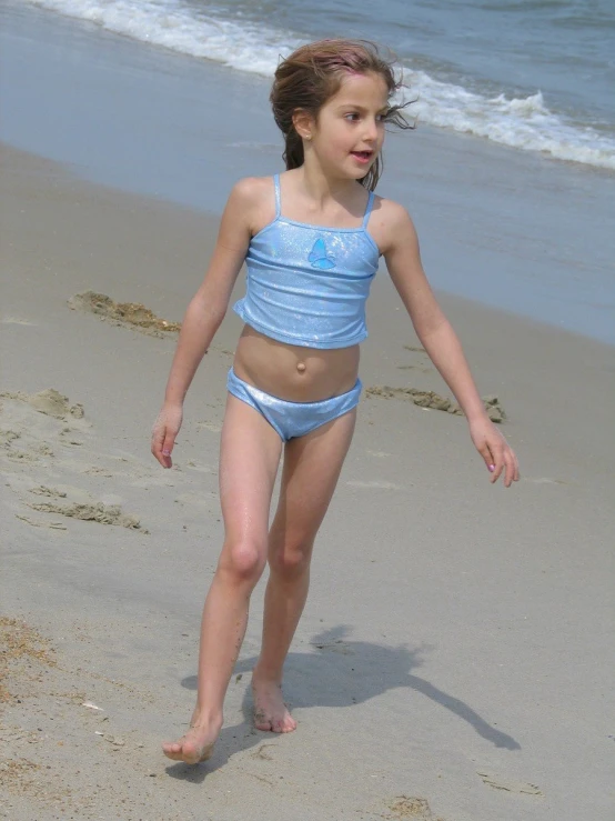 a girl with her bare stomach, wearing blue, on the beach