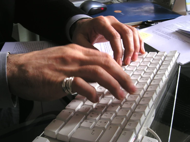 hands typing on a keyboard with paper in the background