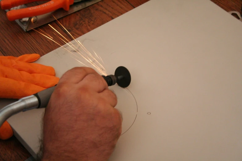 a hand uses a circular hole punch to cut wire