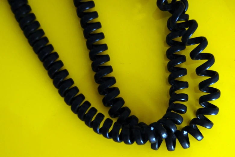 two black cords that are sitting on a yellow background