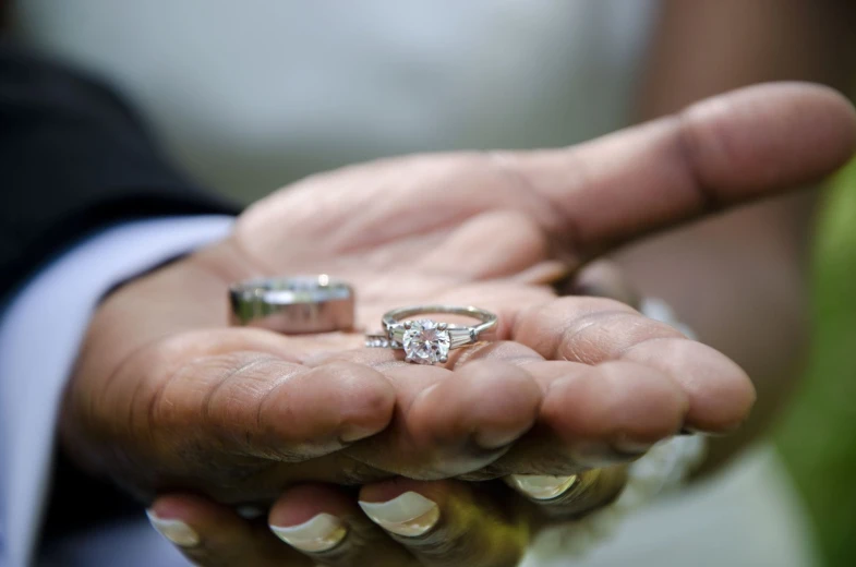 two people holding hands with two diamond rings on each