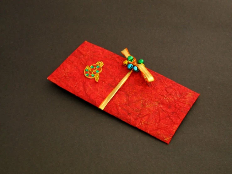 a pair of colorful beads are embedded on a red folded piece of paper