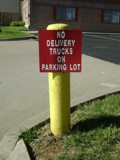 no delivery trucks on parking lot sign posted on a yellow post