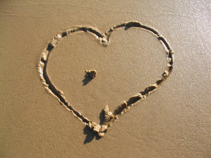 a heart drawn in the sand on a beach