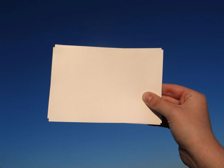 a hand holding a piece of white paper in the air