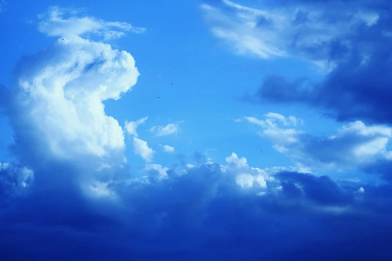 a plane flying through the cloudy blue sky