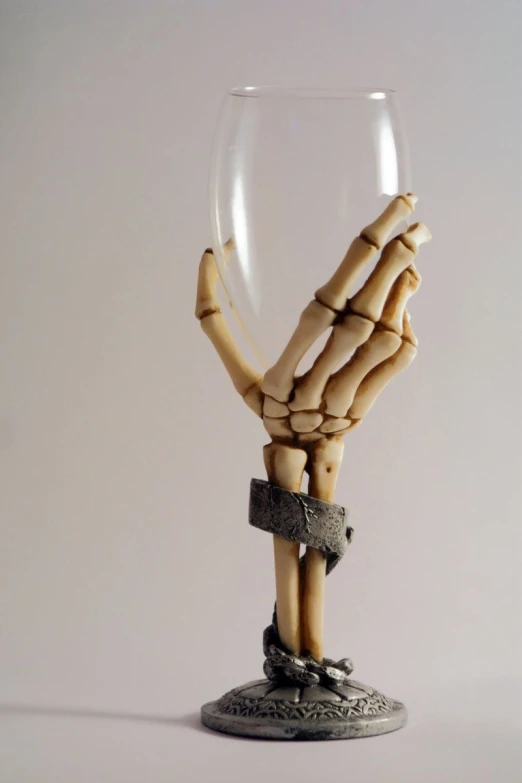 a wine glass with a fake skeleton hand holding the bottom half