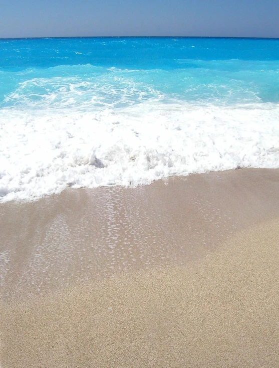 the sky and water line up along a sandy beach