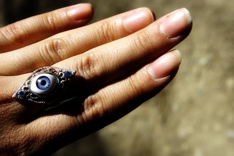 an evil eye ring on a hand with a chain