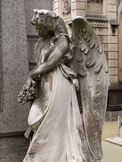 an angel statue with flowers in its hands is next to the cross