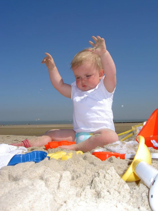 a little toddler sitting in the sand playing