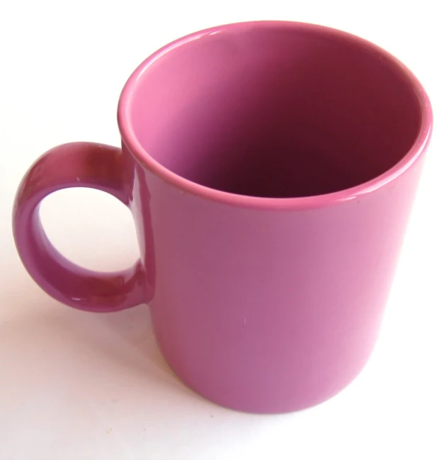 a pink mug is next to some kind of lid