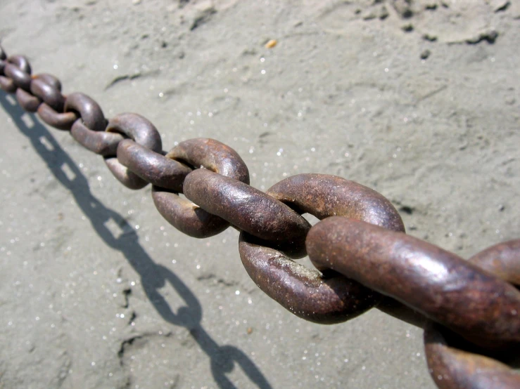 a brown chain attached to the beach next to the water