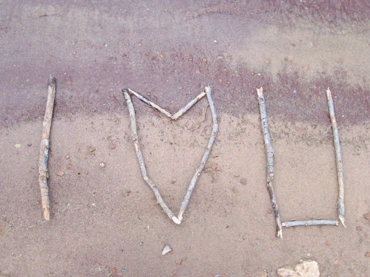 a written in sand with various sticks and nails