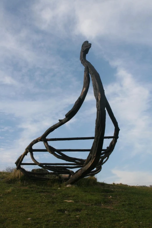 a sculpture of a long piece of wood on a grassy hill