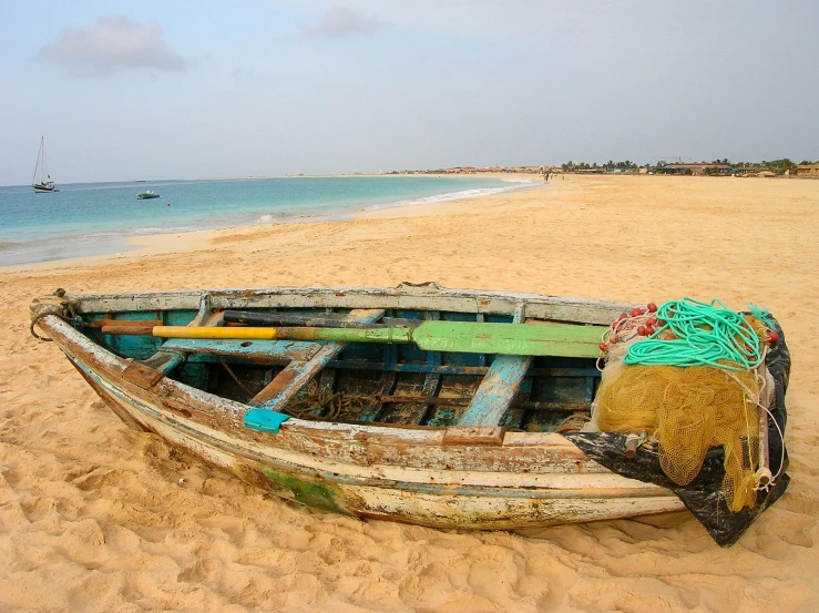 a boat sits on the sand near a body of water