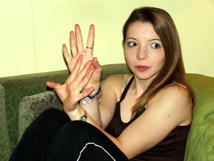 a woman sitting on top of a green couch holding her hands up