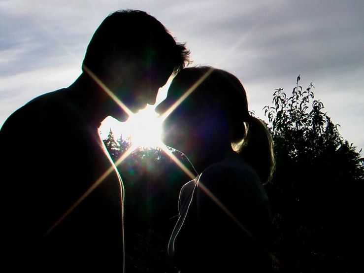 couple kissing in silhouette against the sun