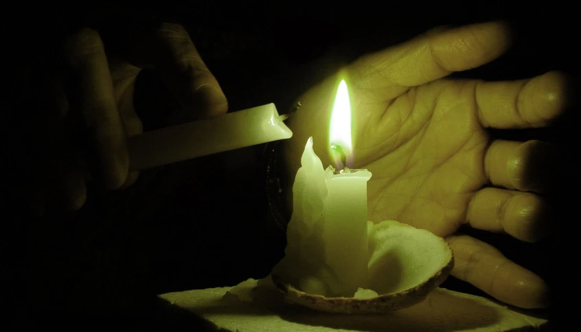 person holding candle with one hand open in dark