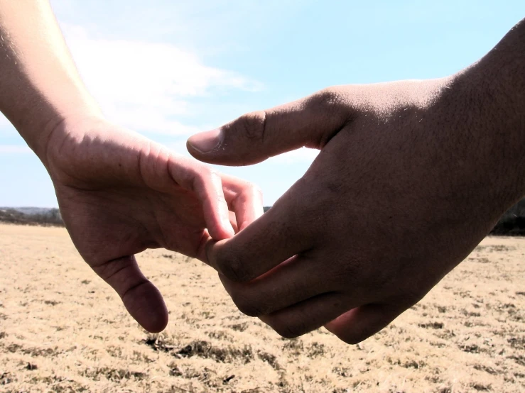 two people holding hands and touching each other on the beach