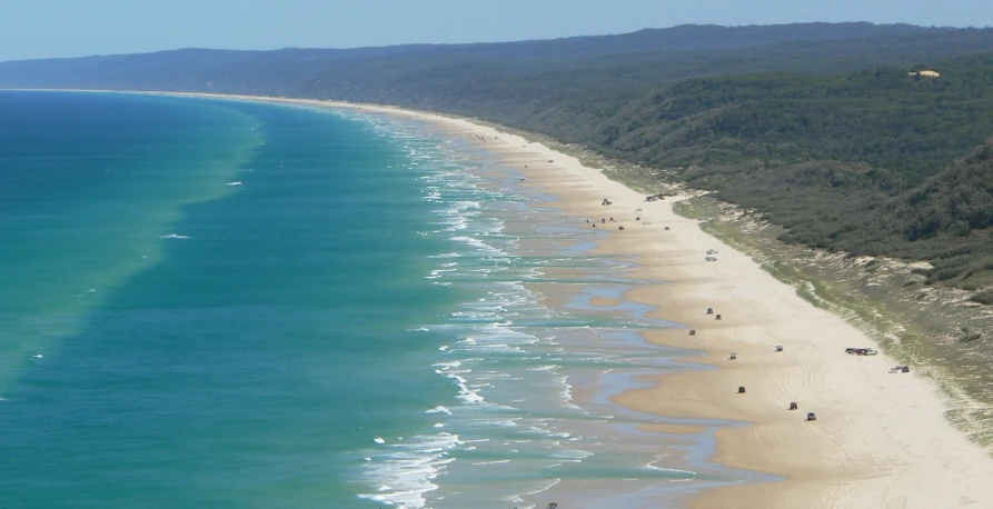 people walk along a wide beach in the water