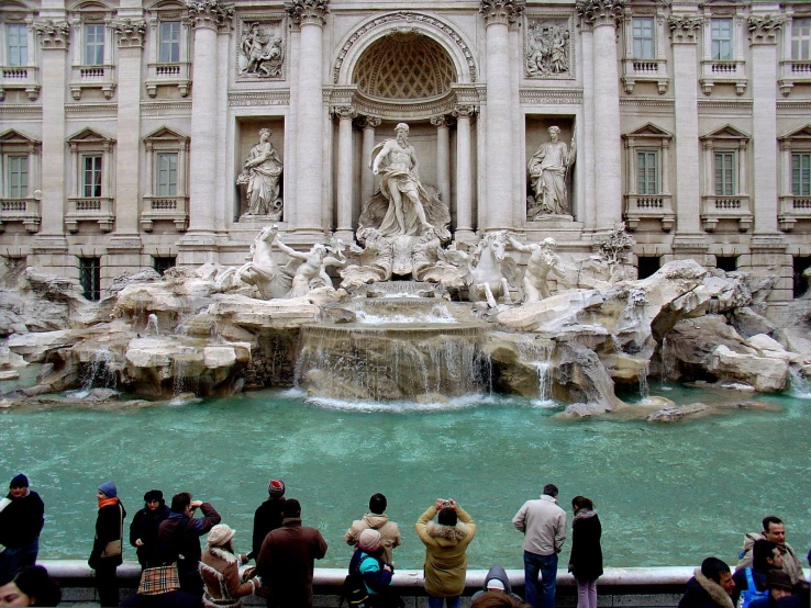 several people standing by a fountain in front of a building