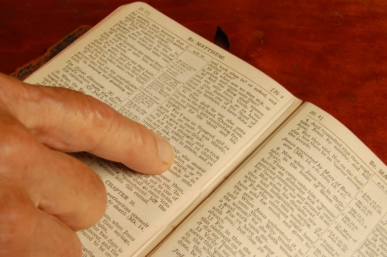 a hand is pointing at a book on a table