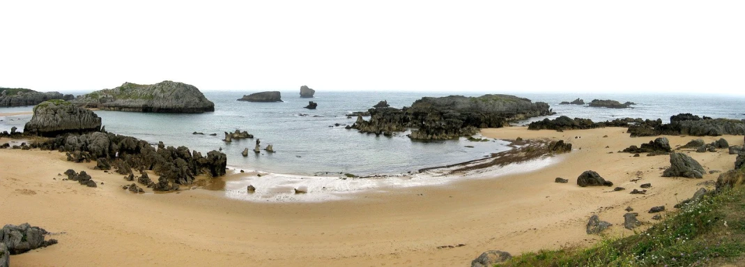 beach with many rocks and sand next to ocean