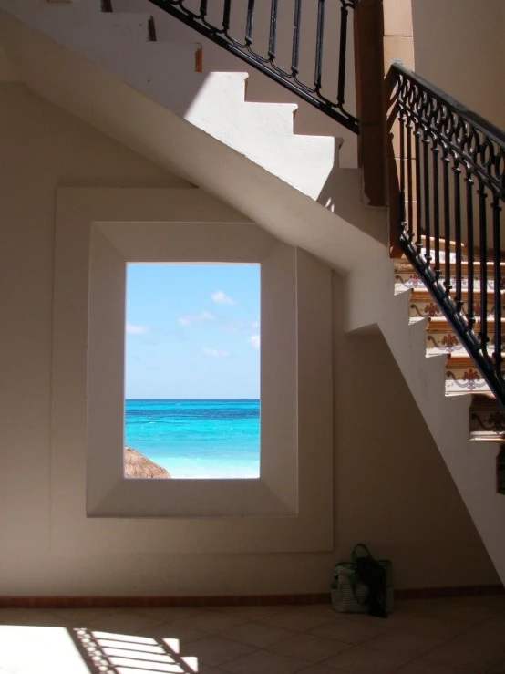 the staircase in front of the windows shows a view of the ocean