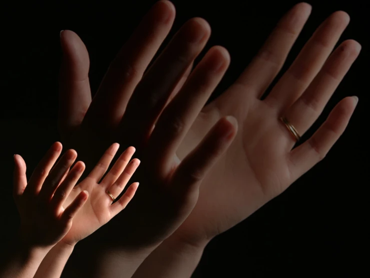 four hands reaching towards the sky with an invisible light