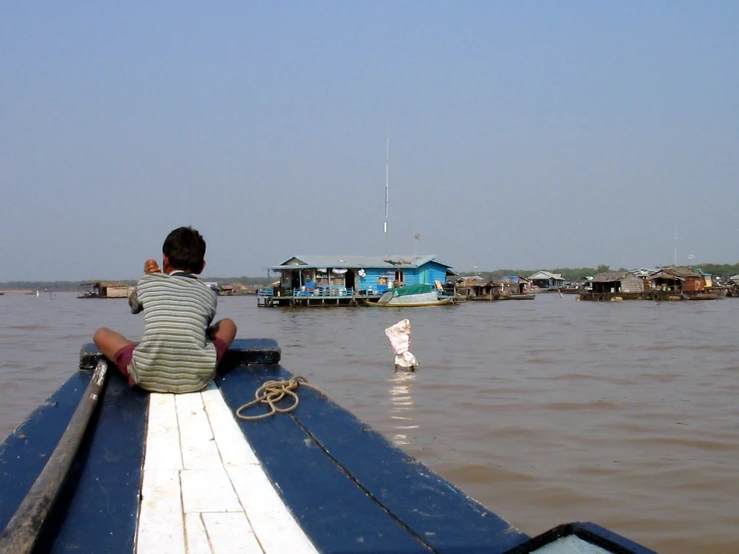 a small child sitting on top of a boat in the water