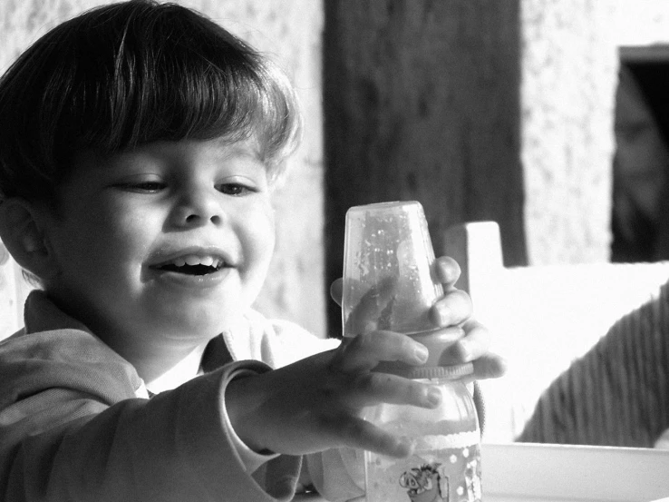 a small child holding a bottle with a piece of paper in it