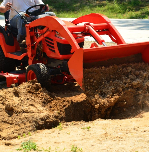 a man riding on a tractor behind a large pile of dirt