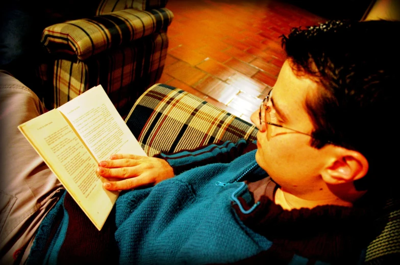 man sitting in a chair and reading a book