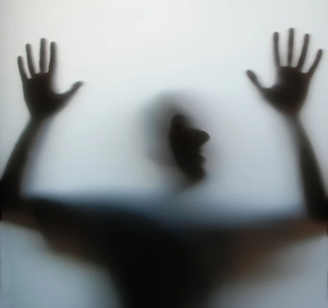 the shadow of a person with their hands in front of a white wall