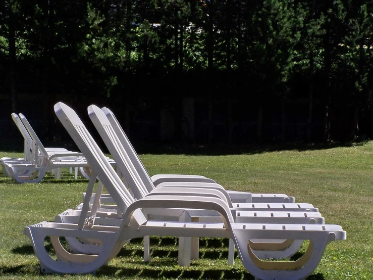 a group of white lawn chairs with one set of four at the end