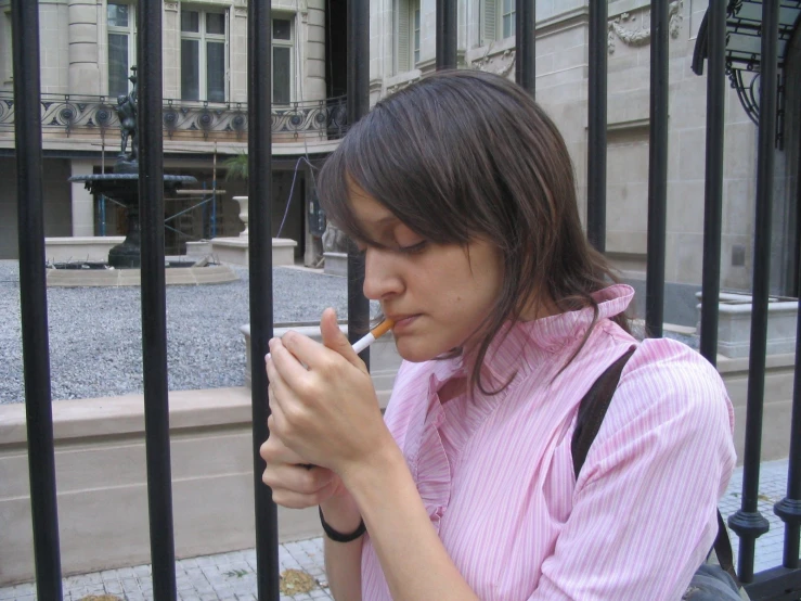 a young woman smoking and standing behind bars