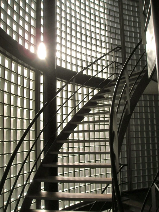 the stairs lead up to the elevator and the sun shines through the glass wall