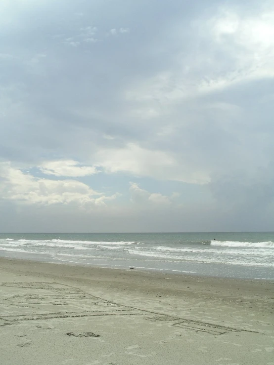 a person is standing on the beach, with his surfboard up to their feet