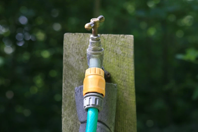 an old fashioned faucet with a green hose attached to it