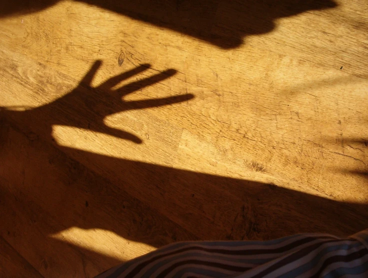 two hands are seen against the surface of an old wooden floor