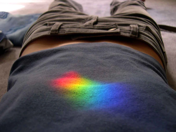 a person is laying down with rainbow lights on their back