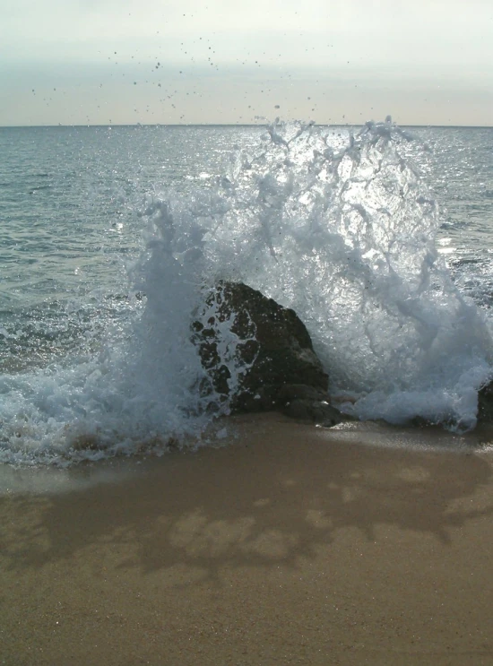 waves crashing onto rocks on a sandy beach