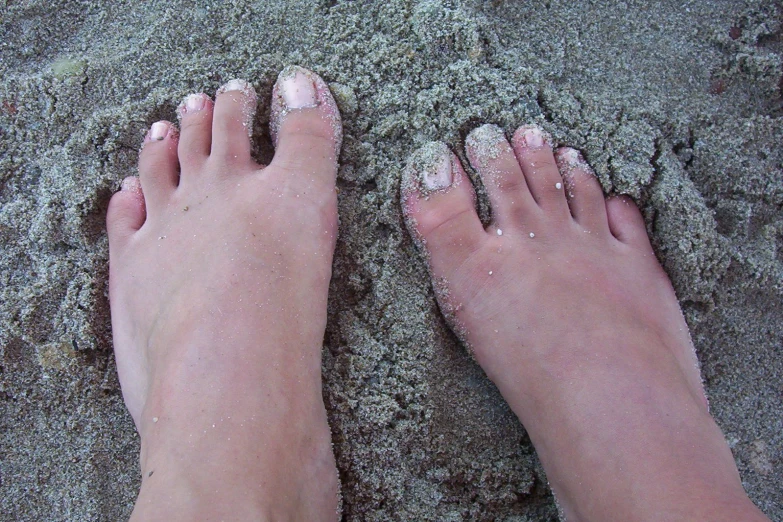 feet and ankles are covered with sand as it is almost completely white