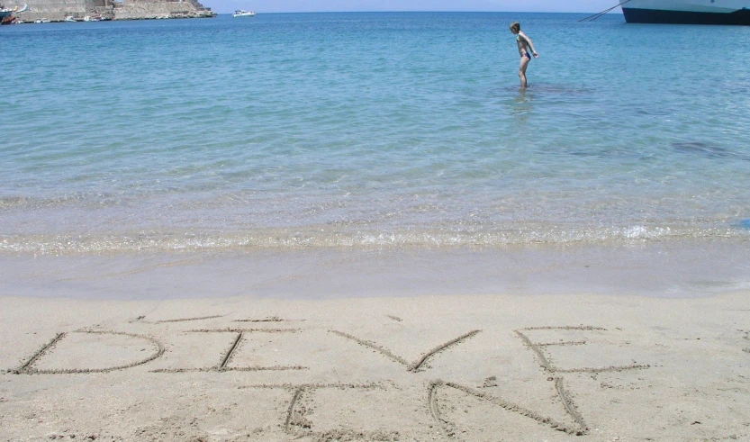 a man walking across a sandy beach near the ocean