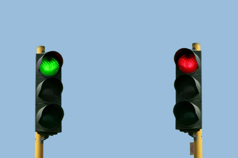 a red and a green traffic signal against a blue sky